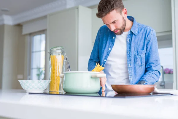 Hombre guapo cocinando pasta en casa — Foto de Stock