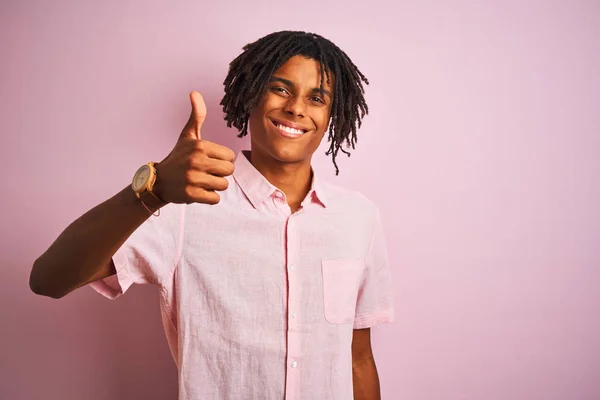 非洲裔美国男子与恐怖锁穿着优雅的衬衫站在孤立的粉红色背景做快乐的拇指手势与手 批准表达式 以显示成功的相机 — 图库照片