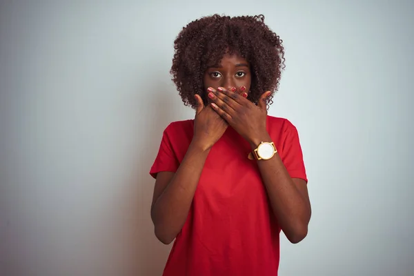 孤立した白い背景の上に赤いTシャツを着た若いアフリカのアフロ女性は 間違って手で口を覆うショックを受けました 秘密の概念 — ストック写真