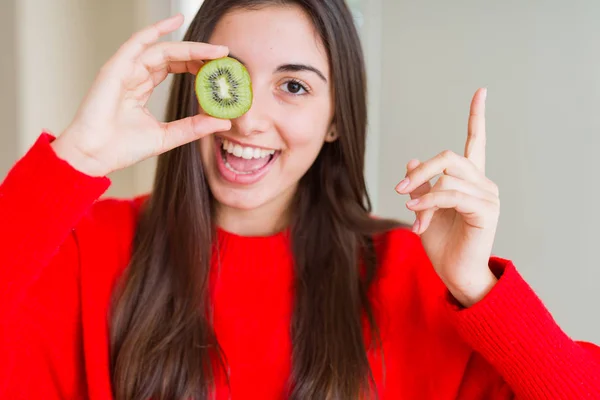 Молодая Женщина Съедающая Половину Свежего Зеленого Киви Довольна Показывая Рукой — стоковое фото