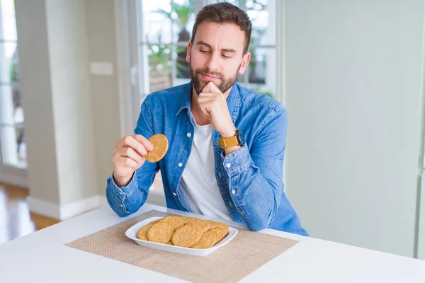 Handsome man eating healthy whole grain biscuit serious face thinking about question, very confused idea
