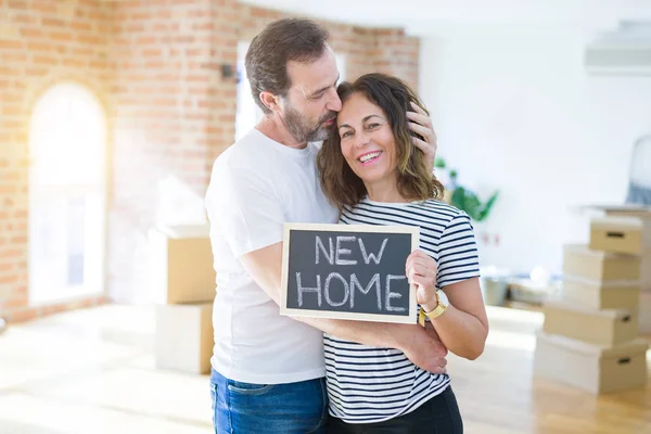 Orta yaş Senior çift yeni bir eve hareket, yeni bir ev metin ile bir tahta tutan Apartmant aşık mutlu gülümseyen