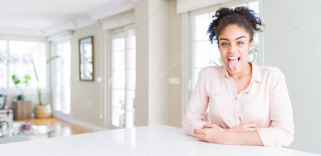 Wide angle of beautiful african american woman with afro hair sticking tongue out happy with funny expression. Emotion concept.
