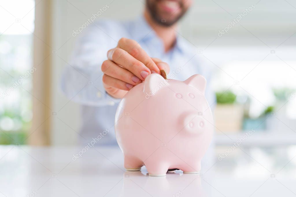 Close up of man hand putting a coin inside of piggy bank as savi