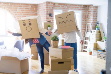 Çılgın çift kafa üzerinde komik yüzler ile kutuları giyiyor, yeni bir eve taşımak için mutlu eğlenceli