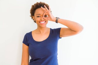 Beyaz arka plan üzerinde genç güzel afro-amerikan kadın el gülümseyerek ok jest yapıyor, mutlu yüz ile parmaklardan bakan göz.