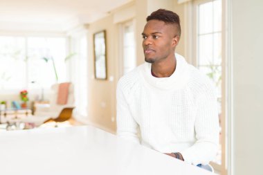 Yakışıklı afro-amerikan adam beyaz masada yan bakıyor, kendine güvenen gülümseme ile doğal yüzü ile profil poz dinlenmek.