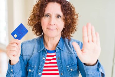 Kıdemli kadın açık el ile ödeme olarak kredi kartı tutan ciddi ve emin ifade ile stop işareti yapıyor, savunma jest