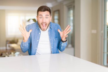 Genç yakışıklı adam evde deli ve başarı için hayran kaldırdı Kollarını açarak kutluyor ve heyecanlı çığlık gözleri açık. Kazanan kavramı