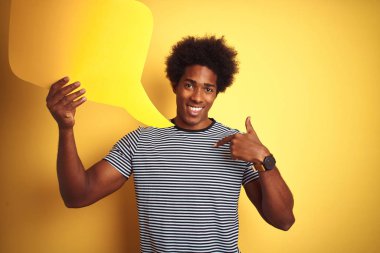 Genç afro-amerikan adam kendini işaret parmak işaret sürpriz yüzü ile izole sarı arka plan üzerinde duran konuşma balonu tutan