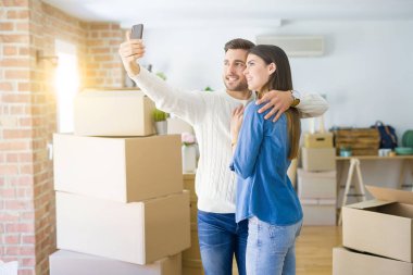 Yeni daire akıllı telefon kullanarak bir selfie fotoğraf çekerken güzel çift, yeni ev için mutlu gülümseyen