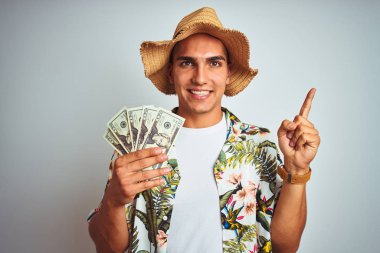 Tatilde beyaz izole arka plan üzerinde dolar banka notları tutan genç adam çok mutlu yan el ve parmak ile işaret