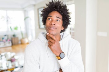 Afrika kökenli Amerikalı adam çene düşünme hakkında soru, dalgın ifade üzerine el ile kazak giyiyor. Düşünceli yüzüyle gülümsüyor. Şüphe kavramı.