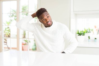 Afro-Amerikan yakışıklı beyaz masa üstünde şaşırtmak ve soru hakkında merak ediyorum. Şüphe, kafasına el ile düşünme ile belirsiz. Dalgın kavramı.