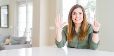 Evde gösteren ve parmakları ile işaret eden güzel genç kadın kendinden emin ve mutlu gülümserken yedi numara.