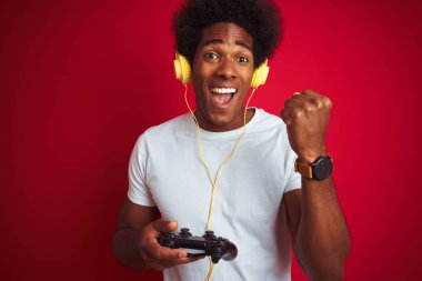Afro oyun adam izole kırmızı arka plan üzerinde joystick kulaklık kullanarak video oyunu oynarken gurur çığlık ve zafer ve başarı çok heyecanlı kutluyor, duygu tezahürat