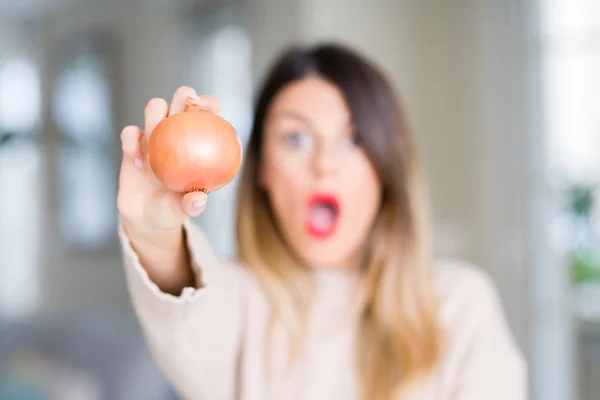 Young Beautiful Woman Holding Fresh Onion Home Scared Shock Surprise — Stock Photo, Image