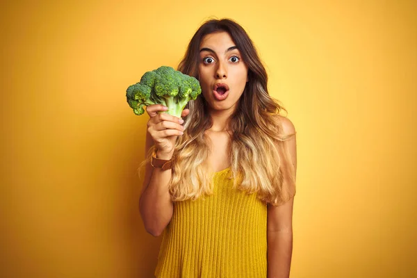 Jovem Mulher Bonita Comendo Brócolis Sobre Amarelo Isolado Fundo Assustado — Fotografia de Stock