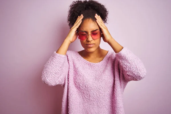 孤立したピンクの背景の上に冬のセーターとサングラスを身に着けているアフリカ系アメリカ人女性は 頭痛に苦しんで絶望的で 痛みと偏頭痛のためにストレスを受けました 頭の上に手を置く — ストック写真