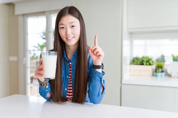 美丽的亚洲女人喝一杯新鲜的牛奶惊讶与想法或问题指向手指与快乐的脸 — 图库照片