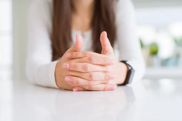 Close up of woman crossed hands over white table — Stock Photo, Image