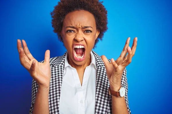 Izole mavi arka plan üzerinde Afro-Amerikan iş yönetici kadın deli ve deli bağırarak ve agresif ifade ve kollar kaldırdı ile bağırıyor. Hayal kırıklığı kavramı.