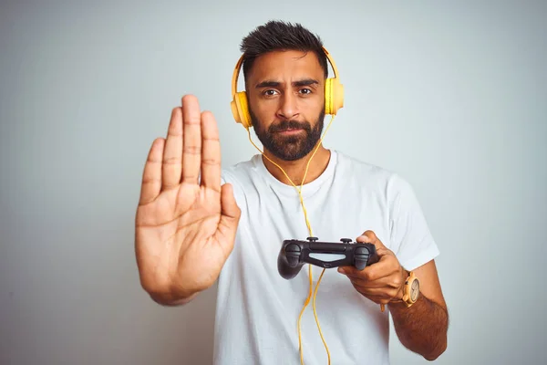 アラブのインドのゲーマーの男は 真剣で自信に満ちた表情で停止サインを行うオープンハンドで孤立した白い背景の上にヘッドフォンを使用してビデオゲームをプレイし 防衛ジェスチャー — ストック写真