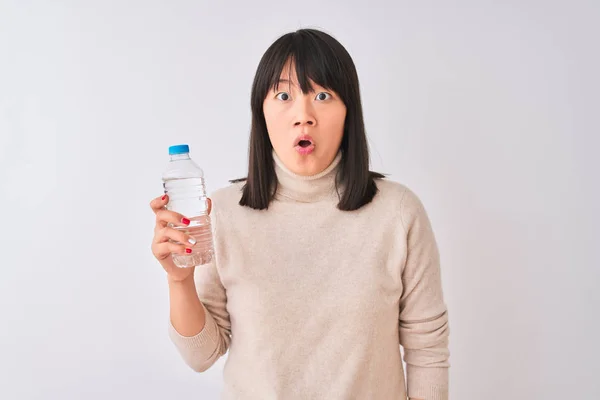 年轻漂亮的中国女人拿着瓶装水在孤立的白色背景害怕在震惊与惊讶的脸 害怕和兴奋与恐惧的表情 — 图库照片