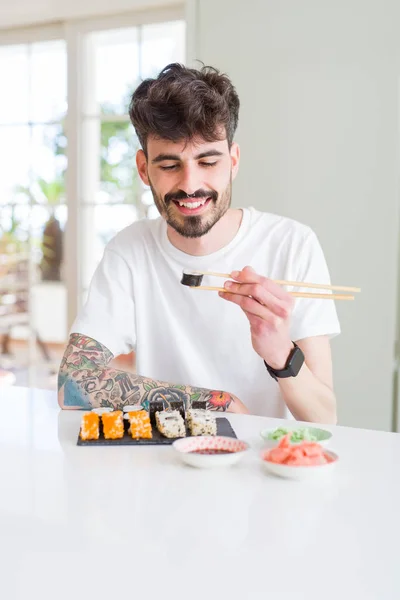 Young man eating sushi asian food using choopsticks