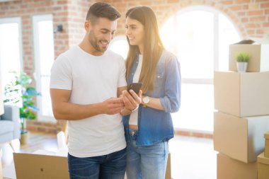 Yeni bir eve hareketli genç çift, yeni daire için çok mutlu gülümseyen Smartphone kullanarak