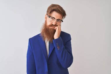 Genç kızıl İrlandalı işadamı takım elbise ve gözlük giyen izole beyaz arka plan düşünme yorgun görünümlü ve çapraz kolları ile depresyon sorunları ile sıkılmış.