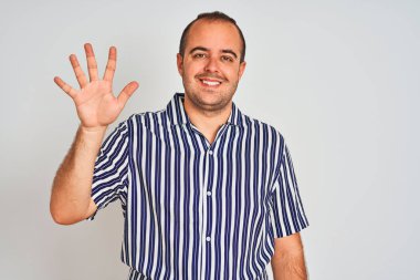 Mavi çizgili gömlek giyen genç adam izole beyaz arka plan üzerinde duran gösteren ve emin ve mutlu gülümserken parmakları ile beş işaret.