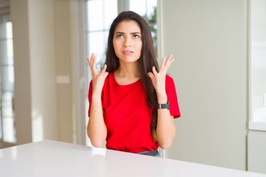 Beyaz masa çılgın ve deli bağırma ve agresif ifade ve kollar ile bağırarak Evde Genç güzel kadın kaldırdı. Hayal kırıklığı kavramı.