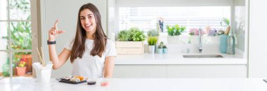 Teslimattan asya suşi yiyen güzel genç kadının geniş açılı resmi gülümseyerek ve kendinden emin bir şekilde el ile el yaparken parmaklarla işaret ve kamera. Ölçü kavramı.