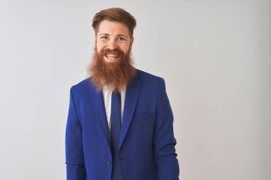 Genç kızıl saçlı İrlandalı işadamı yüzünde mutlu ve serin bir gülümseme ile izole beyaz arka plan üzerinde duran takım elbise giyiyor. Şanslı kişi.