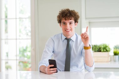 Ofiste akıllı telefon kullanan genç iş adamı mutlu yüz, bir numaralı ile bir fikir veya soru işaret parmağı ile şaşırttı