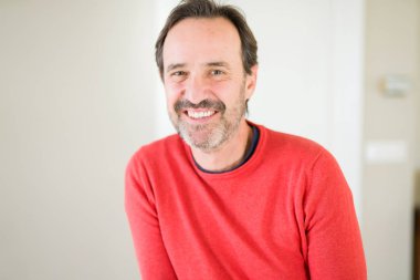 Evde kameraya bakarak gülümseyen yakışıklı orta yaş erkek