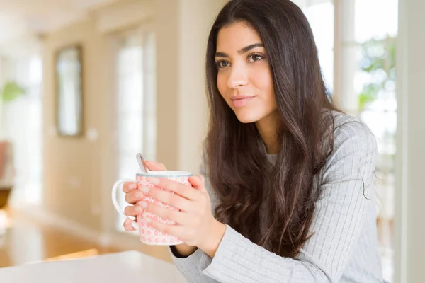 Schönes junges Mädchen trinkt zu Hause eine Tasse Kaffee und lächelt — Stockfoto