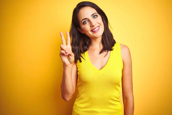 노란색 서있는 티셔츠를 아름다운 여성은 자신감과 행복한 미소를 지으면서 손가락 — 스톡 사진