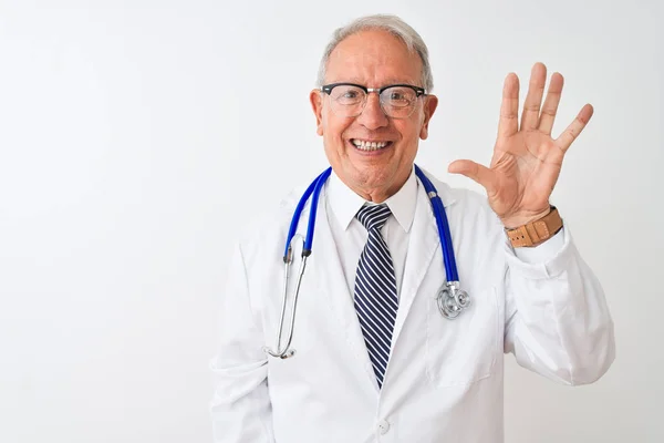 孤立した白い背景の上に立つ聴診器を身に着けた先輩の灰色の医者の男は 自信を持って幸せに微笑みながら 指番号5を示し 指で上向きにする — ストック写真