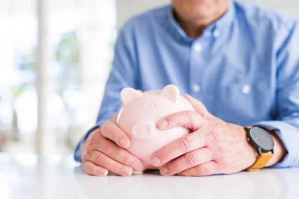 Homem segurando porquinho banco com cuidado, economizando dinheiro para a aposentadoria — Fotografia de Stock