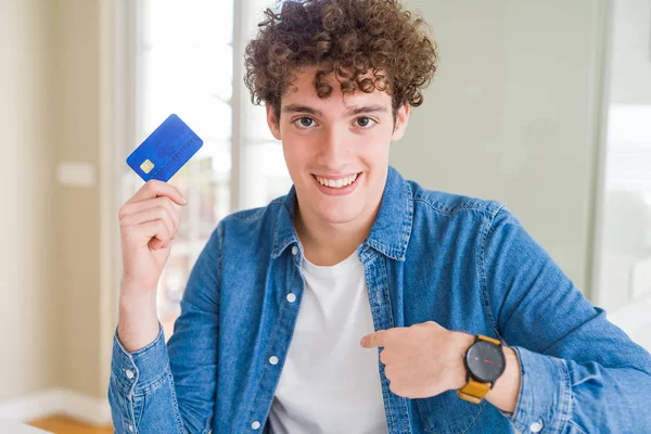 Joven Sosteniendo Tarjeta Crédito Con Cara Sorpresa Señalando Dedo Mismo —  Fotos de Stock