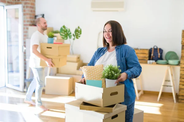 Young couple moving to new apartment, beautiful woman moving cardboard boxes and smiling happy