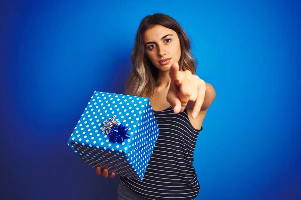 Young Woman Holding Birthday Present Blue Isolated Background Pointing Finger — Stock Photo, Image