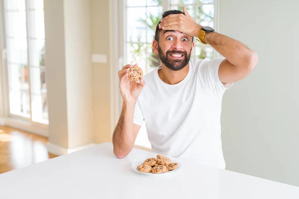 Όμορφος Ισπανικός Άνθρωπος Τρώει Τσιπ Σοκολάτας Χέρι Στο Κεφάλι Σοκαρισμένος — Φωτογραφία Αρχείου
