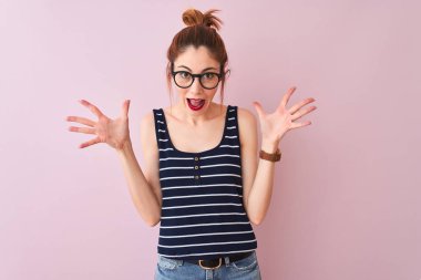 Redhead kadın pigtail giyen çizgili t-shirt izole pembe arka plan üzerinde deli kutluyor ve silah kaldırdı ve açık gözleri ile başarı için hayran heyecanlı çığlık giyen. Kazanan kavramı