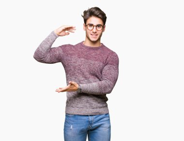 Büyük ve büyük boy işaret, ölçü birimi sembol gösteren ellerle eller izole arka plan üzerinde gözlük takan yakışıklı delikanlı. Kameraya bakarak gülümsüyordu. Ölçüm kavramı.