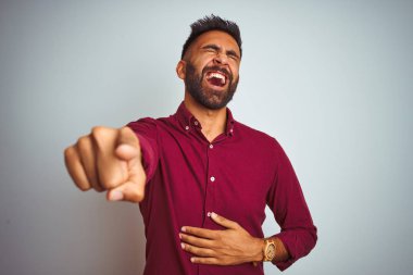Kırmızı zarif gömlek giyen genç hintli adam izole gri arka plan üzerinde duran size gülüyor, vücut üzerinde el ile kameraya parmak işaret, utanç ifade