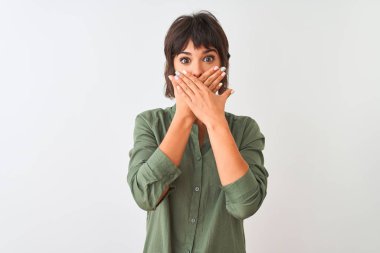 Izole beyaz arka plan üzerinde duran yeşil rahat gömlek giyen genç güzel kadın hata için elleri ile ağız kapsayan şok. Gizli kavram.