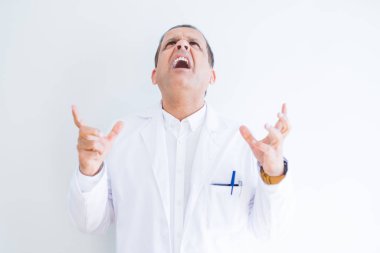 Orta yaş doktor adam beyaz arka plan üzerinde tıbbi ceket giyen deli ve deli bağırarak ve agresif ifade ve kolkaldırdı ile bağırıyor. Hayal kırıklığı kavramı.